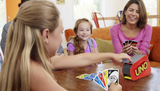 Family enjoying playing Uno Attack with the updated card launcher and colorful cards at a table.