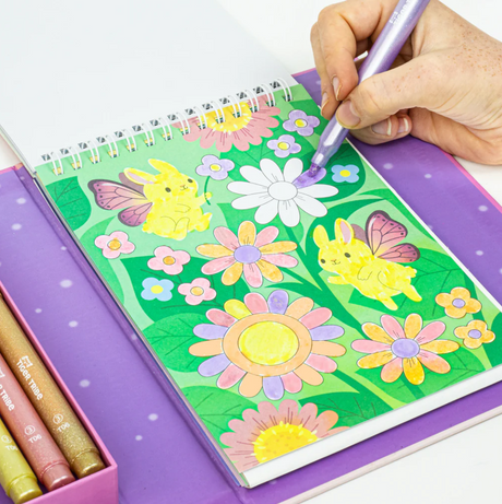 Coloring Set | Little Fairy Land with sparkly shimmer markers coloring fairy-winged hamsters and flowers in a spiral-bound book.