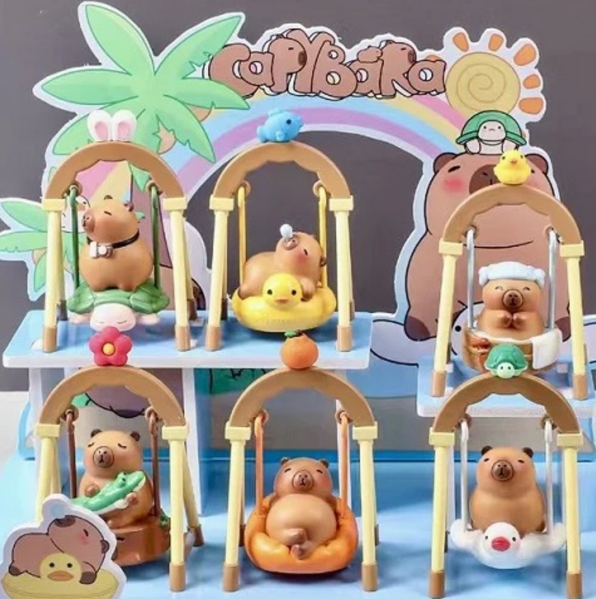 Capybara Swing Blind Box featuring cute capybara figurines on swings with playful animal designs and colorful backdrop.