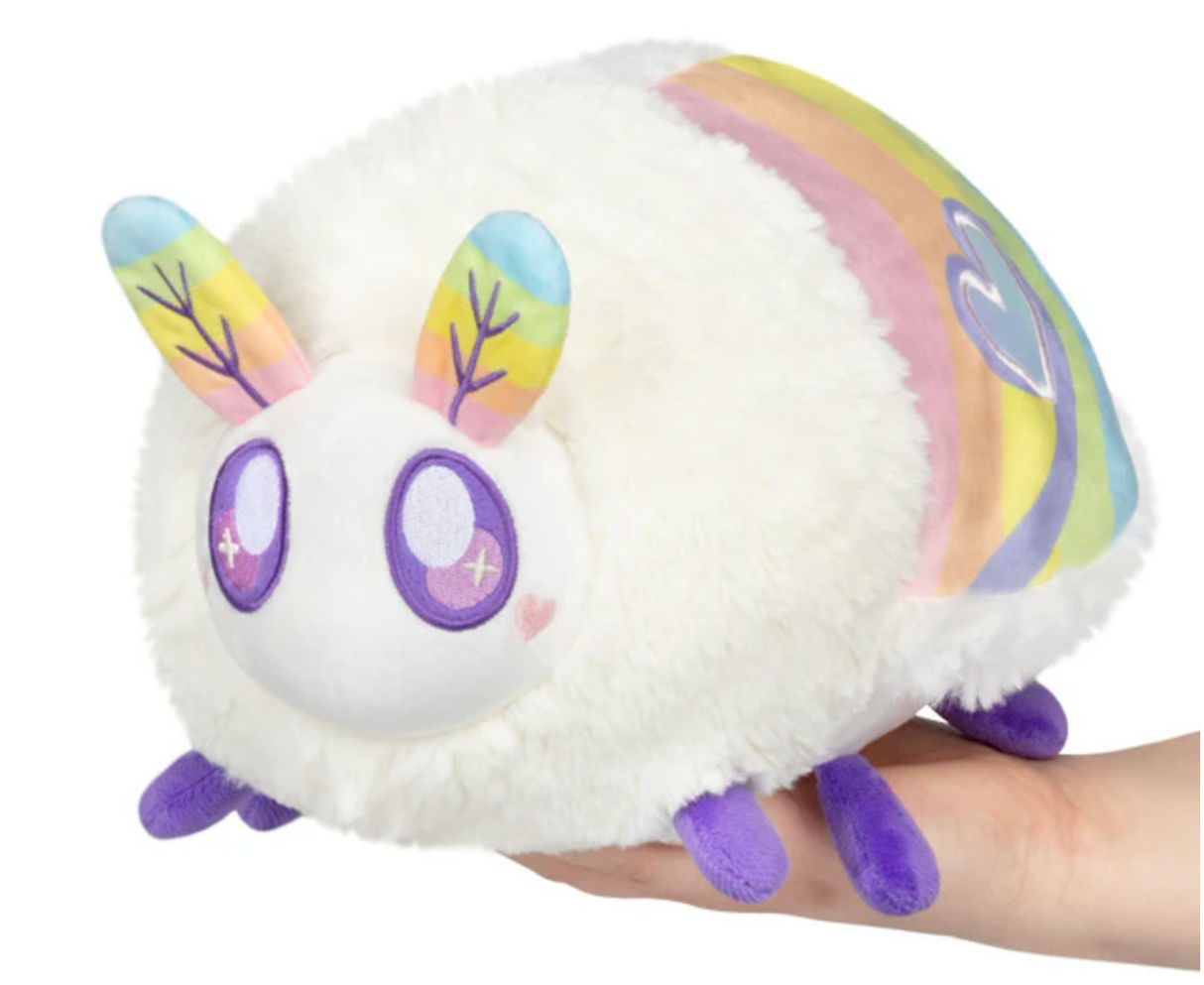 Hand holding the Prism Moth Mini plush toy with fluffy white body and colorful rainbow wings.