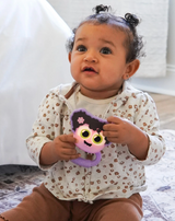 Baby holding Glo Pals Light Up Rattle Purple with glowing eyes, promoting sensory and motor skill development.
