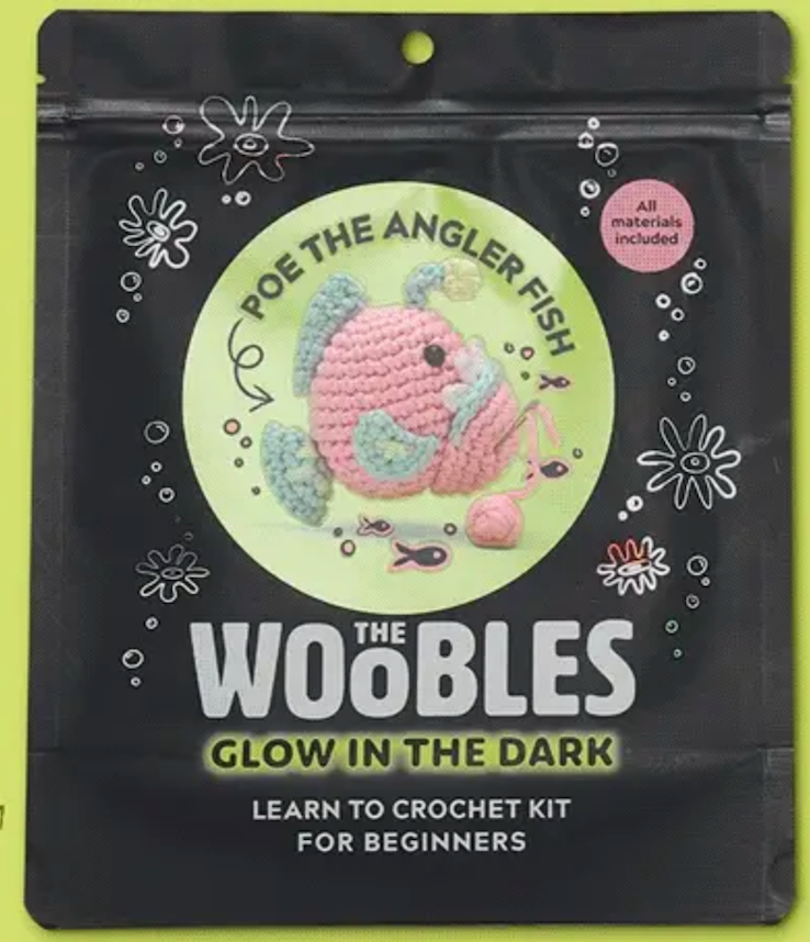 Poe the Angler Fish crochet kit packaging showing a pink and blue crocheted fish with glow in the dark yarn included.