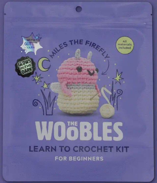 Purple crochet kit packaging featuring a cute pink and cream firefly plush that glows in the dark