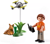 Play figure flying a drone near a resting fawn and green plants in a forest rescue adventure set.