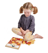 Young girl sitting cross-legged playing with a colorful patchwork quilt puzzle made of triangular pieces