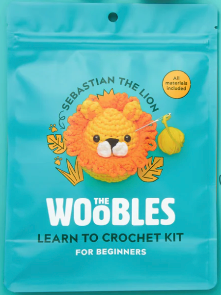 Blue package for The Woobles crochet kit featuring Sebastian the Lion with bright orange mane and yarn ball included.