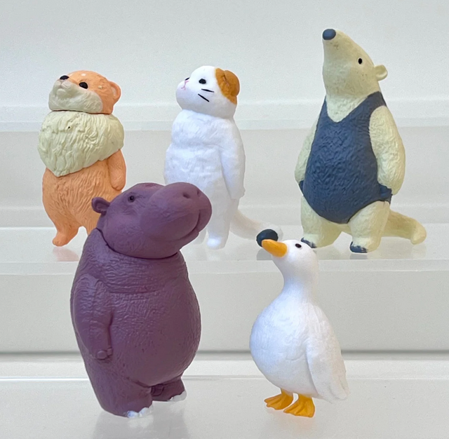 Five colorful plastic animal figurines including a bear, hippo, duck, hamster, and otter standing on clear platforms.