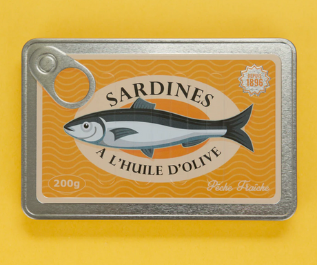 Vintage sardine tin-style notebook with textured metal cover and playful olive oil design on yellow background