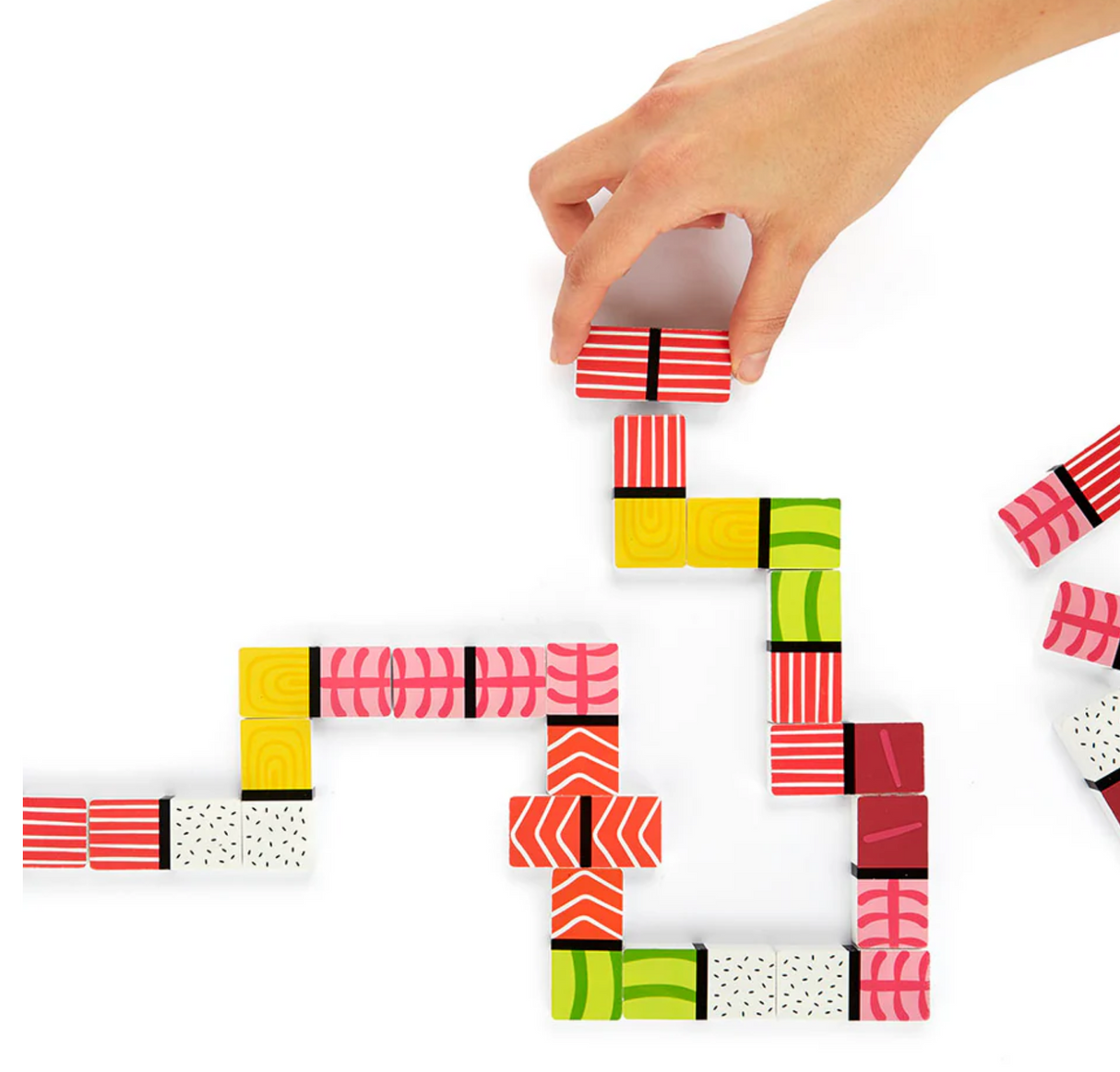 Hand placing a red-striped sushi-inspired domino piece on a colorful wooden sushi domino game set.