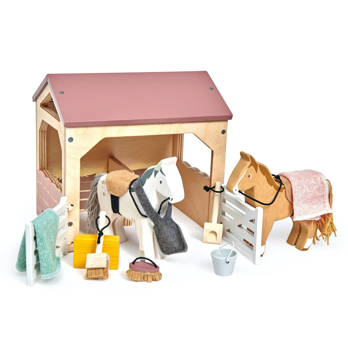 The Stables wooden toy set with two ponies, grooming tools, blankets, bucket, and stable for kids 3 years and older.