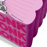 Close-up of a thick, purple scalloped-edge notepad with bold pink text and lined pink sheets for notes and doodles