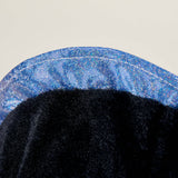 Close-up of soft black plush fabric with shiny blue trim on a Warmies Black Axolotl toy