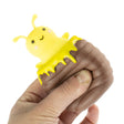 Hand squeezing Peek A Boo Bee toy revealing a smiling yellow bee inside a hive-shaped sensory toy.
