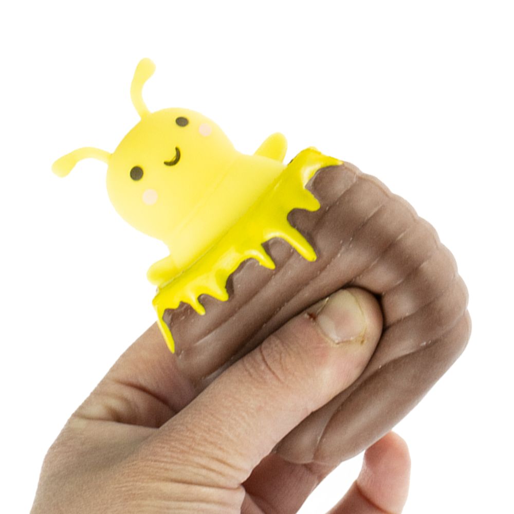 Hand squeezing Peek A Boo Bee toy revealing a smiling yellow bee inside a hive-shaped sensory toy.