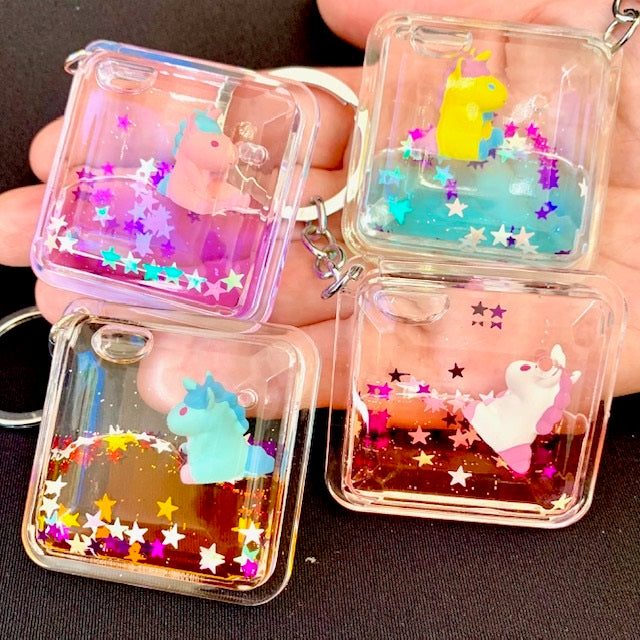 Floating Unicorn KeyChain with colorful glitter and assorted unicorn designs in clear square casing.