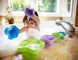 Child playing with colorful Stacking Cups in a bubbly bathtub, scooping and pouring water during bath time.