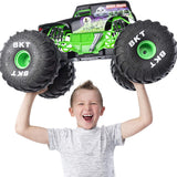 Young boy holding the HUGE RC Grave Digger monster truck with large BKT tires and authentic graphics above his head.