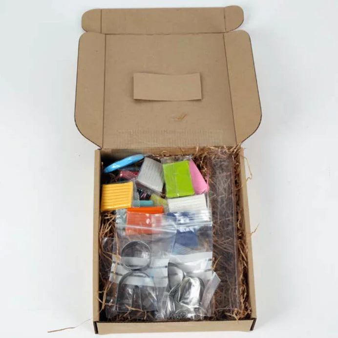 Open box showing Crafters Polymer Clay Jewelry kit with colorful clay blocks and earring and necklace forms inside.
