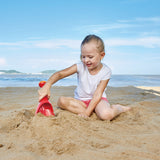 Child playing on the beach with a red toy shovel, not the Rain Shovel Blue product shown in the listing.