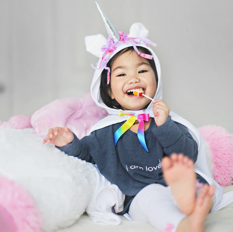 Baby White Unicorn Cape | Size 2-3 on a smiling toddler with silver horn and bright multicolored mane bow tie