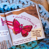Blanket: Journey to Extreme Coziness with an open picture book showing a butterfly and cozy blue knitted blanket.