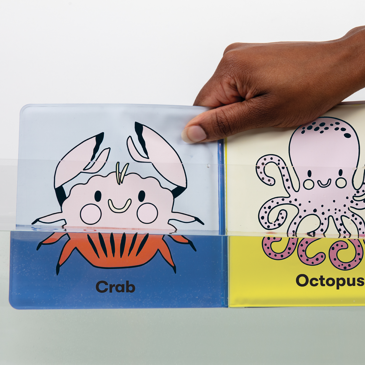 Bath Book Color Magic | Color the Ocean shows a hand dipping a crab page with color appearing underwater.