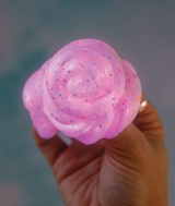 Glowbrights Enchanting Unicorn Thinking Putty glowing pink with rainbow glitter held in hand.